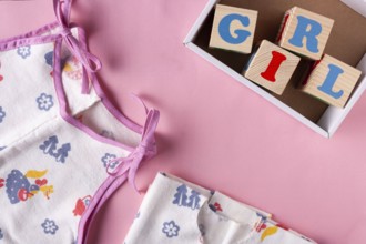 Clothes for a newborn girl and wooden cubes with letters Girl