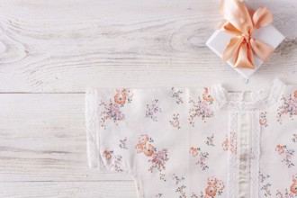 Shirt for newborn toddler and gift box on white wood