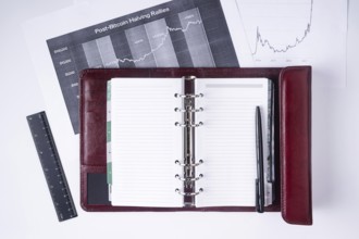 A notebook with a pen lies on financial charts