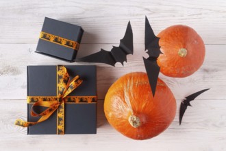 Pumpkin gifts black paper bats on light wood flat lay halloween decor
