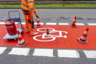 Application of red road surfacing on a cycle lane, inner-city road, so-called cold plastic