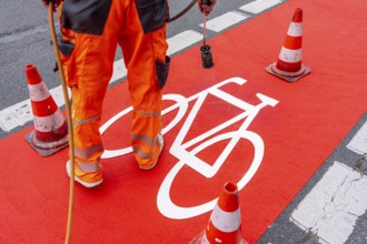 Application of red road surfacing on a cycle lane, inner-city road, so-called cold plastic