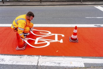 Application of red road surfacing on a cycle lane, inner-city road, so-called cold plastic