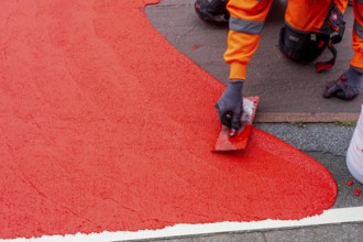 Application of red road surfacing on a cycle lane, inner-city road, so-called cold plastic