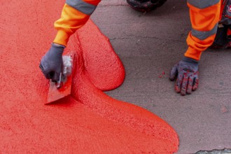 Application of red road surfacing on a cycle lane, inner-city road, so-called cold plastic