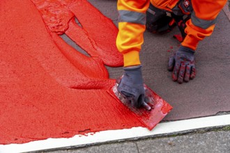 Application of red road surfacing on a cycle lane, inner-city road, so-called cold plastic
