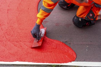 Application of red road surfacing on a cycle lane, inner-city road, so-called cold plastic
