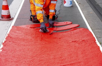 Application of red road surfacing on a cycle lane, inner-city road, so-called cold plastic
