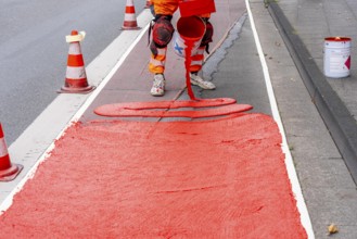 Application of red road surfacing on a cycle lane, inner-city road, so-called cold plastic