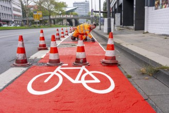 Application of red road surfacing on a cycle lane, inner-city road, so-called cold plastic