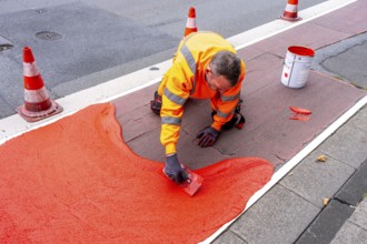 Application of red road surfacing on a cycle lane, inner-city road, so-called cold plastic