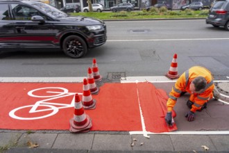 Application of red road surfacing on a cycle lane, inner-city road, so-called cold plastic
