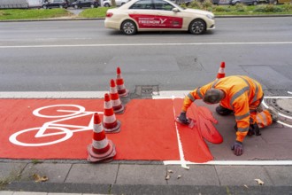 Application of red road surfacing on a cycle lane, inner-city road, so-called cold plastic