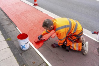 Application of red road surfacing on a cycle lane, inner-city road, so-called cold plastic