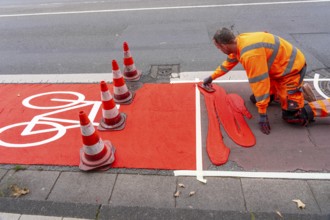 Application of red road surfacing on a cycle lane, inner-city road, so-called cold plastic
