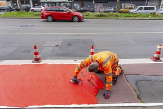 Application of red road surfacing on a cycle lane, inner-city road, so-called cold plastic