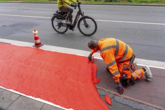 Application of red road surfacing on a cycle lane, inner-city road, so-called cold plastic