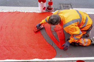 Application of red road surfacing on a cycle lane, inner-city road, so-called cold plastic