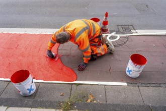 Application of red road surfacing on a cycle lane, inner-city road, so-called cold plastic