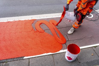 Application of red road surfacing on a cycle lane, inner-city road, so-called cold plastic