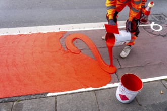 Application of red road surfacing on a cycle lane, inner-city road, so-called cold plastic