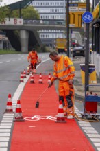 Application of red road surfacing on a cycle lane, inner-city road, so-called cold plastic