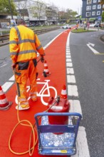 Application of red road surfacing on a cycle lane, inner-city road, so-called cold plastic