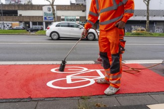 Application of red road surfacing on a cycle lane, inner-city road, so-called cold plastic
