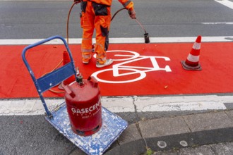 Application of red road surfacing on a cycle lane, inner-city road, so-called cold plastic