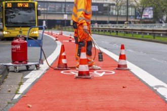 Application of red road surfacing on a cycle lane, inner-city road, so-called cold plastic