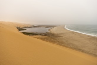 Golden dunes and the Atlantic Ocean near Namib-Naukluft Park, Namibia. A lagoon and shoreline fade