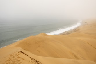 Golden dunes and the Atlantic Ocean near Namib-Naukluft Park, Namibia. A lagoon and shoreline fade