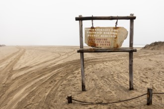 Road sign displaying the name of Namib-Naukluft National Park against a desert landscape under a