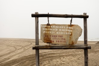 Road sign displaying the name of Namib-Naukluft National Park against a desert landscape under a