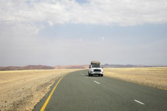 Inside Sossusvlei, gravel roads wind and a car through red dunes to Deadvlei, Big Daddy, and