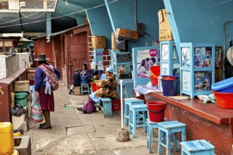 Lively street scene at a Bolivian market with people in traditional clothing and colourful chairs,