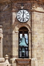 Detail of a clock tower with a large clock and a visible bell in a colonial building, The churches