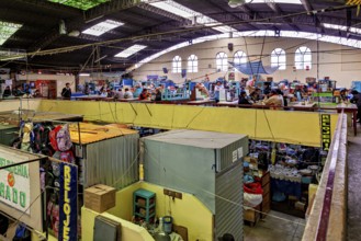 Interior view of a multi-storey market with many stalls and a busy atmosphere under an industrial