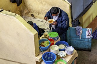 A man eats in a cosy corner with colourful crockery and a laid table, A man eats at a market stall