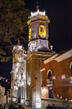 Illuminated church at night, decorated with flags and surrounded by trees, The churches of the city