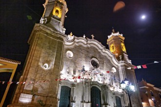 Illuminated church under the night sky with festive lights and flags, The churches of the city of