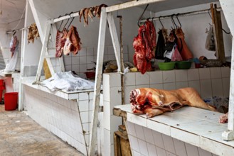 A rustic market stall with raw meat hanging on tiled walls, The meat market in the market halls of