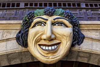 Large, smiling face made of stone and wood, richly decorated as an architectural detail of a