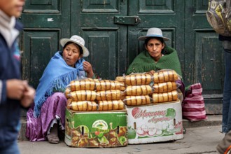 Two woman in traditional dress selling bread on the street, Bolivian Indio woman selling goods in