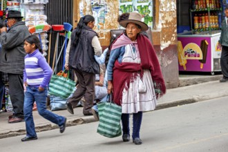 Woman in traditional clothes with bags walking past market stalls on the street, woman and people