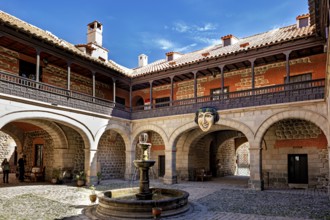 A historic courtyard with a central fountain, surrounded by colonial architecture and stone walls