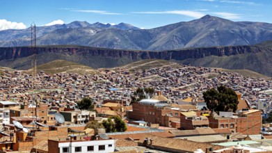 Expansive view of a city against an impressive mountain backdrop with tiled roofs and valleys, view