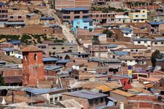 Urban area with orange-coloured roofs in a slightly hilly environment with pastel shades, view over