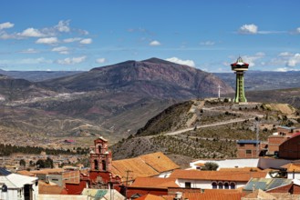 City with red roofs and observation tower, surrounded by mountains under a blue sky, The water
