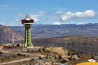 Observation tower on a hill with a cross and clouds in the blue sky in the background, The water